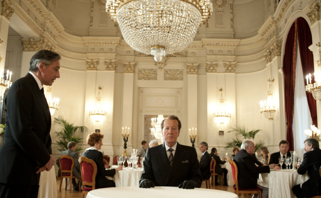 Virgil sits beneath a chandelier in The Best Offer.