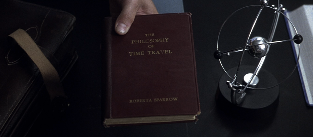 Roberta Sparrow’s The Philosophy of Time Travel beside a metal desk model in Donnie Darko.