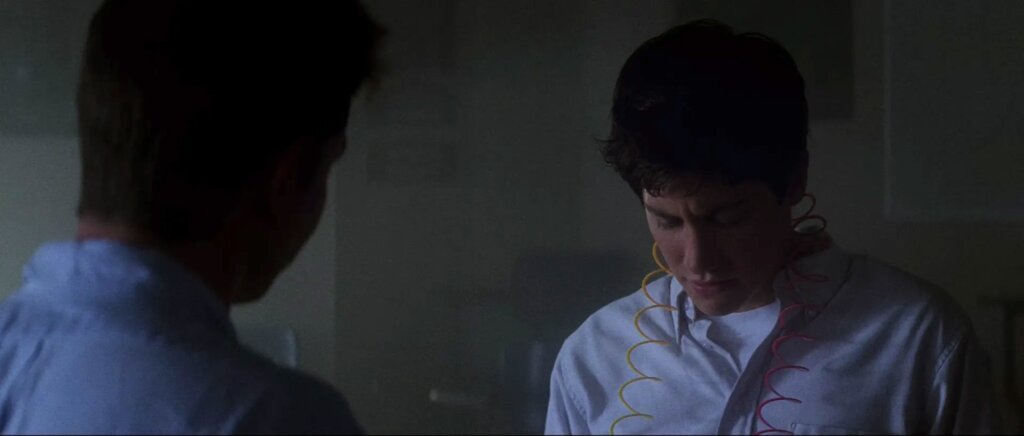 Donnie, with a colored coil around his neck, speaks with his science teacher in Donnie Darko.
