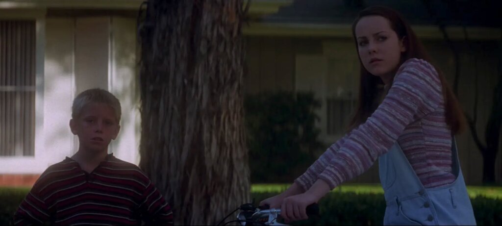 Gretchen pauses with her bicycle beside a boy outside the Darko house in Donnie Darko.