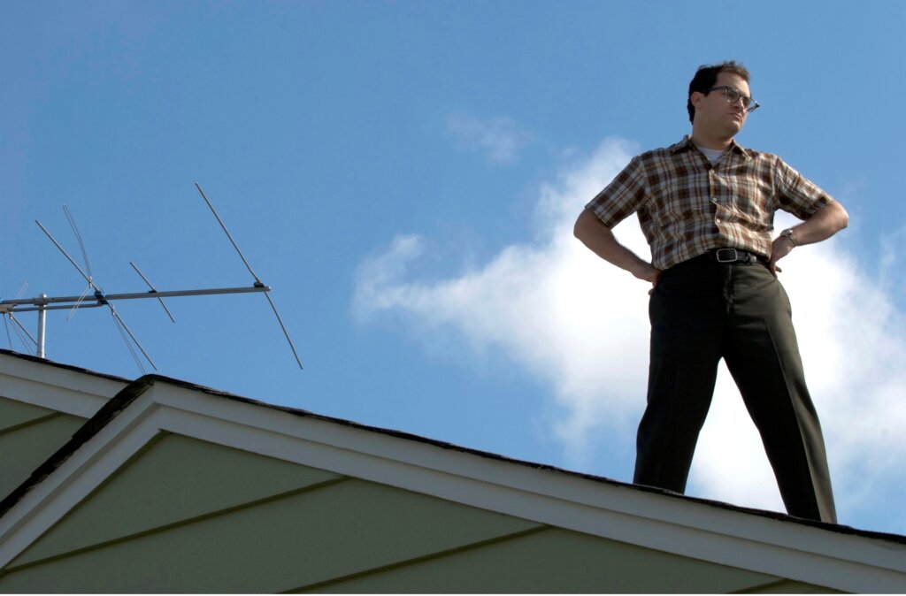 Larry Gopnik stands on his roof beside a television antenna in A Serious Man