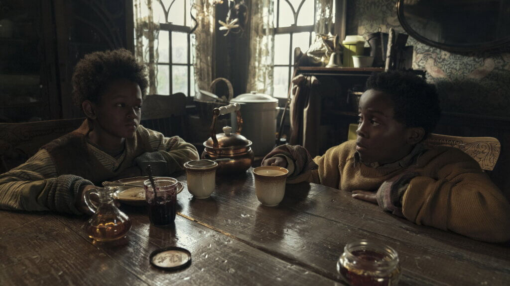Nolan and Samuel sit across from each other at the cabin table in Never Let Go.