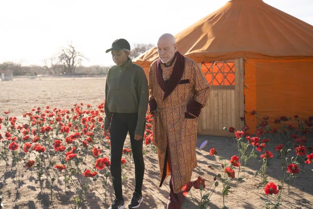 Ariel Ecton walks with Alfred Moretti through the desert compound in Opus (2025)