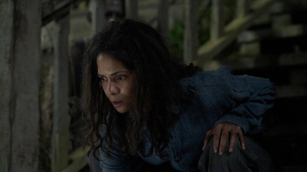 Momma crouches inside the shadowed cabin in Never Let Go.