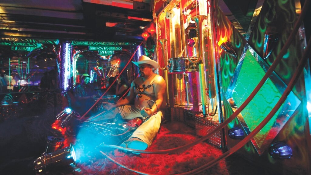 A worker connected to cables operates machinery inside the neon-lit cyberlabor factory in Sleep Dealer.