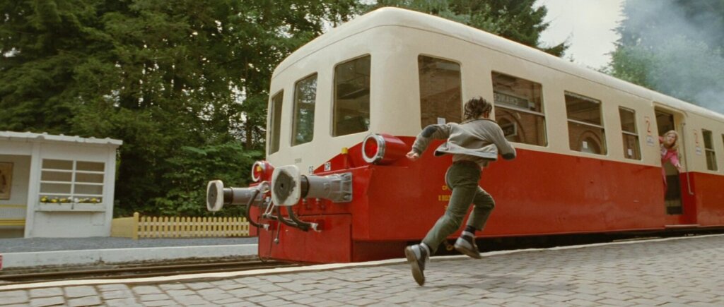 Young Nemo runs beside a departing train while his mother reaches toward him in Mr. Nobody.