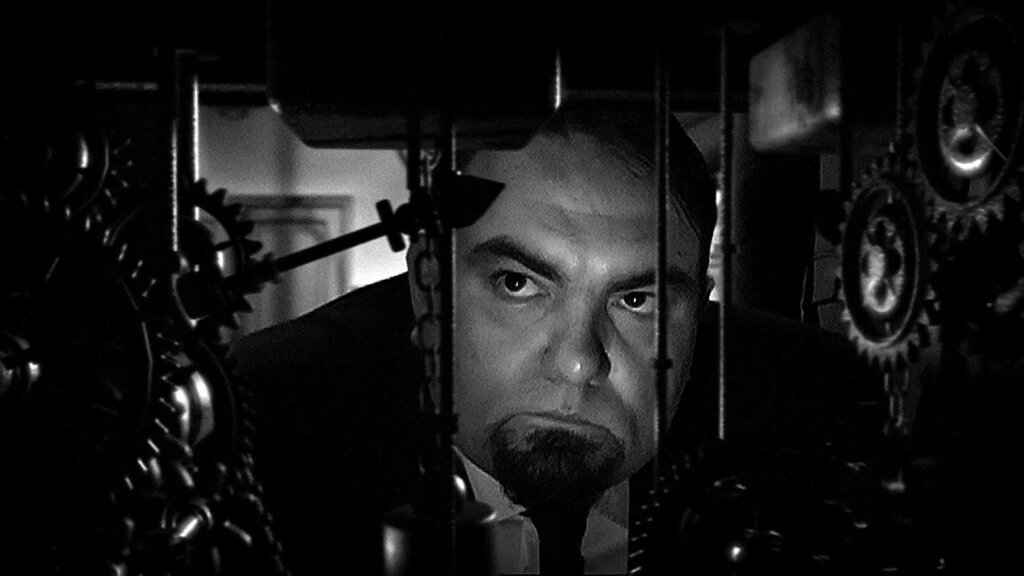 A researcher peers through the gears and rods of a mechanical device in The Laplace’s Demon.