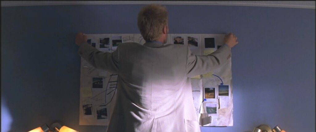 Leonard Shelby assembles Polaroids and handwritten clues on an evidence wall in Memento (2000).