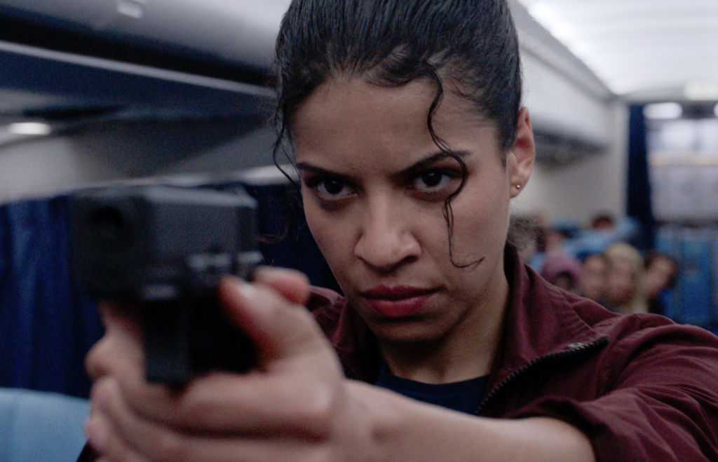 Boadicea Ricketts aims her weapon inside the airplane cabin in Black Box (2026).