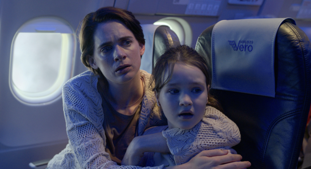A frightened mother protects her daughter during the airborne crisis in Black Box (2026).