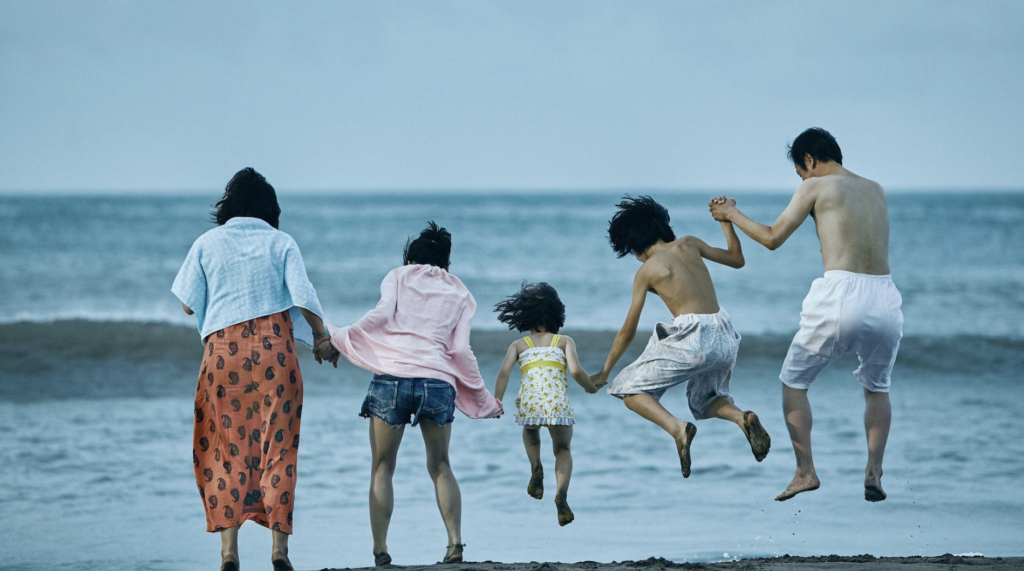 The makeshift family holds hands and jumps into the sea in Shoplifters (2018).