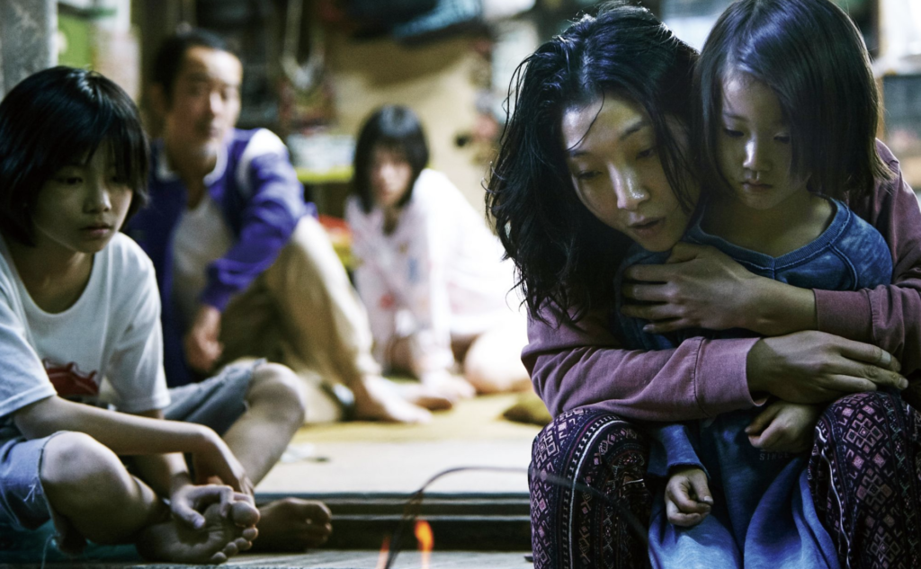 The Shibata family gathers around a small fire inside their crowded home in Shoplifters (2018).