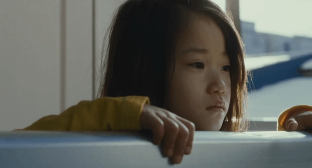 Yuri stands alone at the railing after being separated from the Shibata family in Shoplifters (2018).