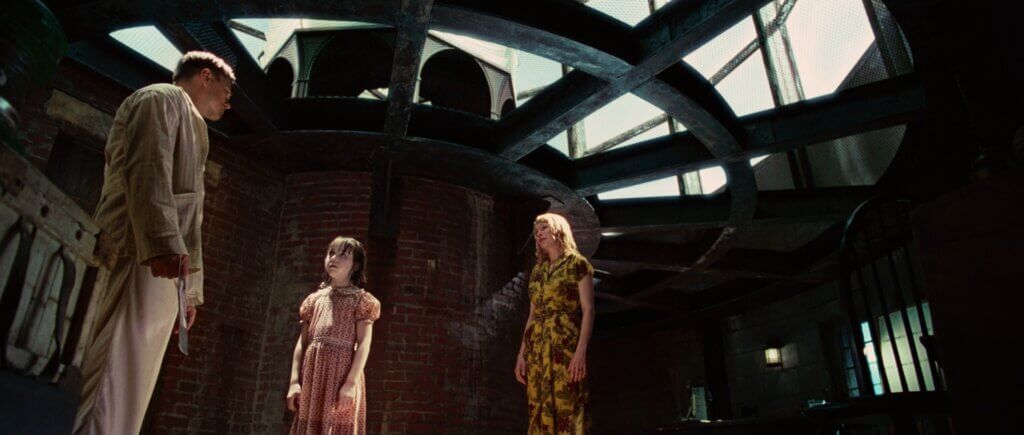 Andrew Laeddis stands with Dolores and a girl inside the lighthouse.