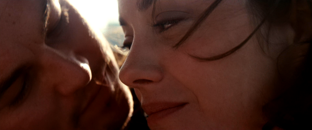 Close-up of Cobb leaning toward Mal as sunlight catches her face in Inception (2010).