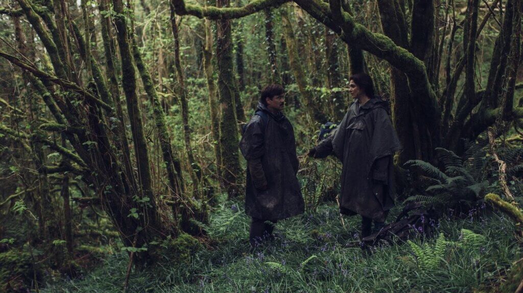David and a woman stand in a wet forest in The Lobster.
