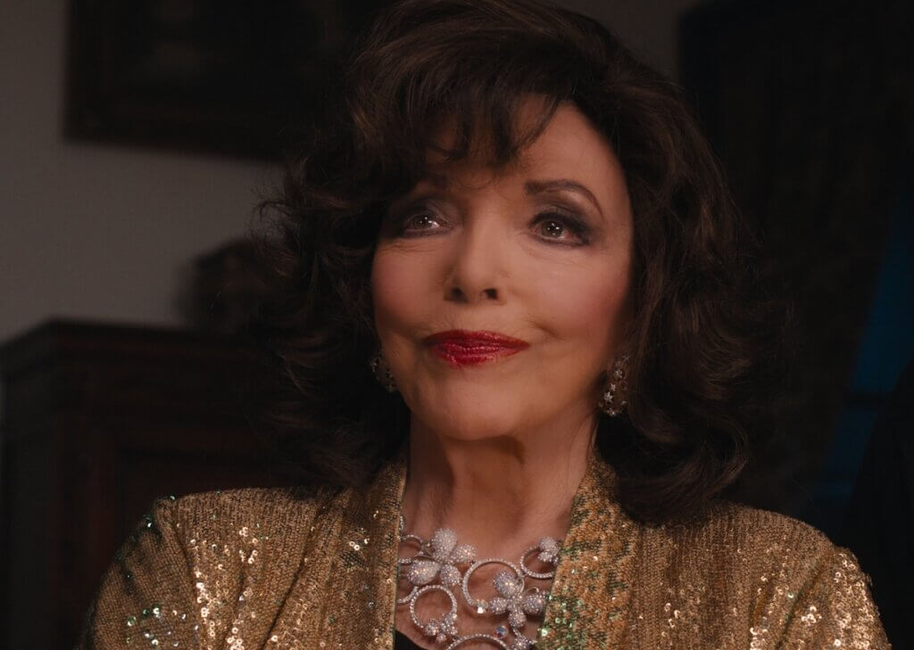Francesca Carlyle (Joan Collins) wears a gold sequined jacket and large silver necklace in A Murder Between Friends (2026).