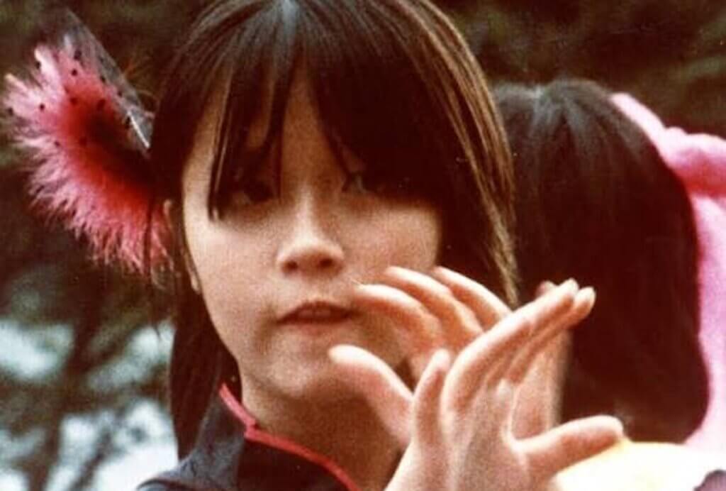 A woman raises here hands in Chris Marker’s Sans Soleil.