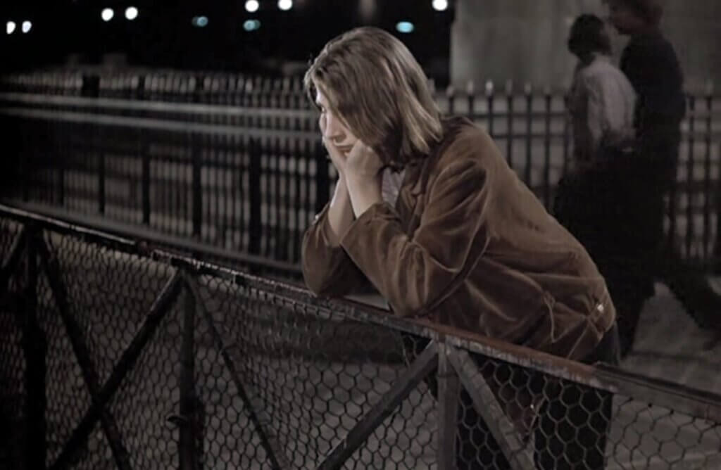 Charles leans against a fence at night in The Devil, Probably.