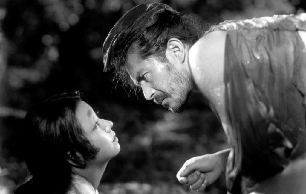 Tajōmaru confronts a woman in the forest in Rashomon.
