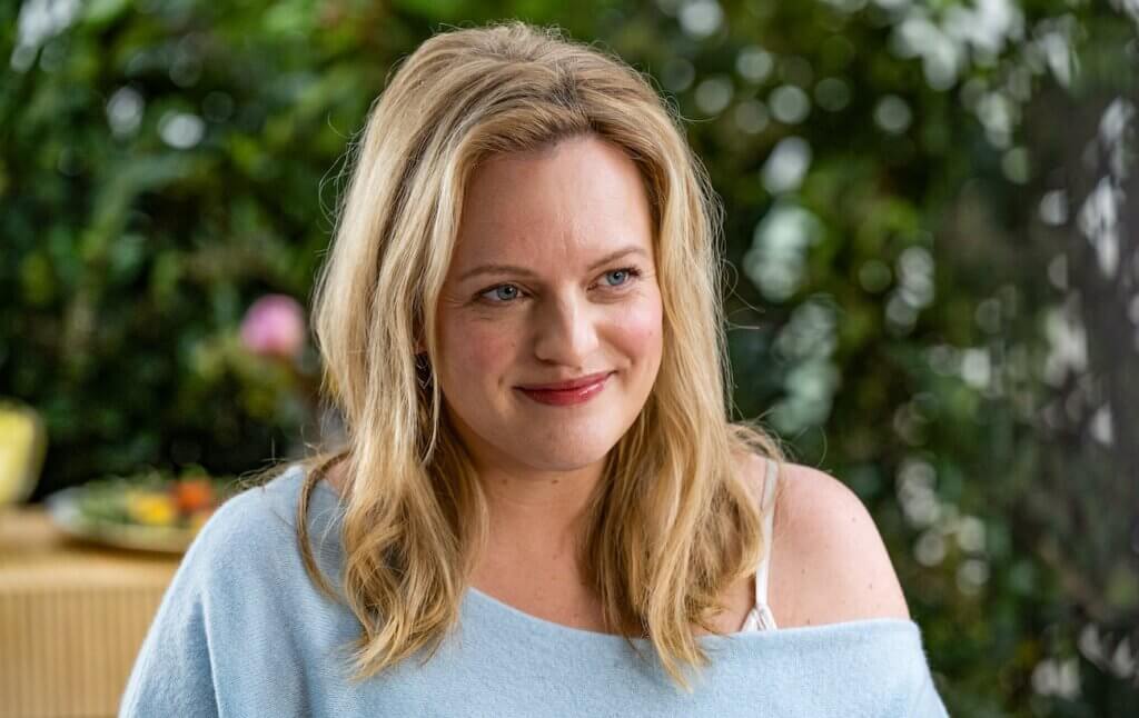 Samantha Lake (Elisabeth Moss) smiles outdoors in a pale blue off-the-shoulder top in Shell (2025).